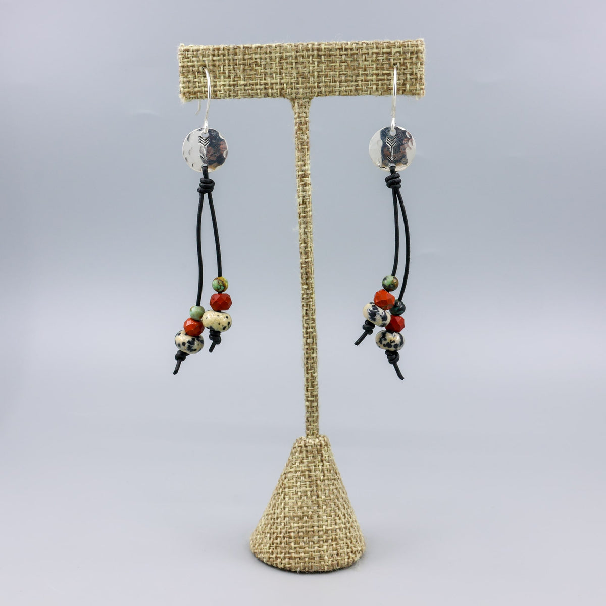 Arrow stamped sterling silver and leather earrings with jasper beads on a linen hanger