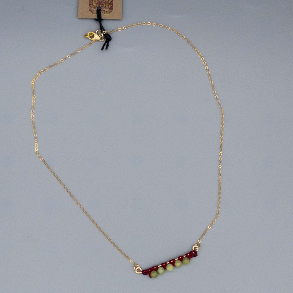 full view of 14k gold filled bar necklace with peridot beads and macrame