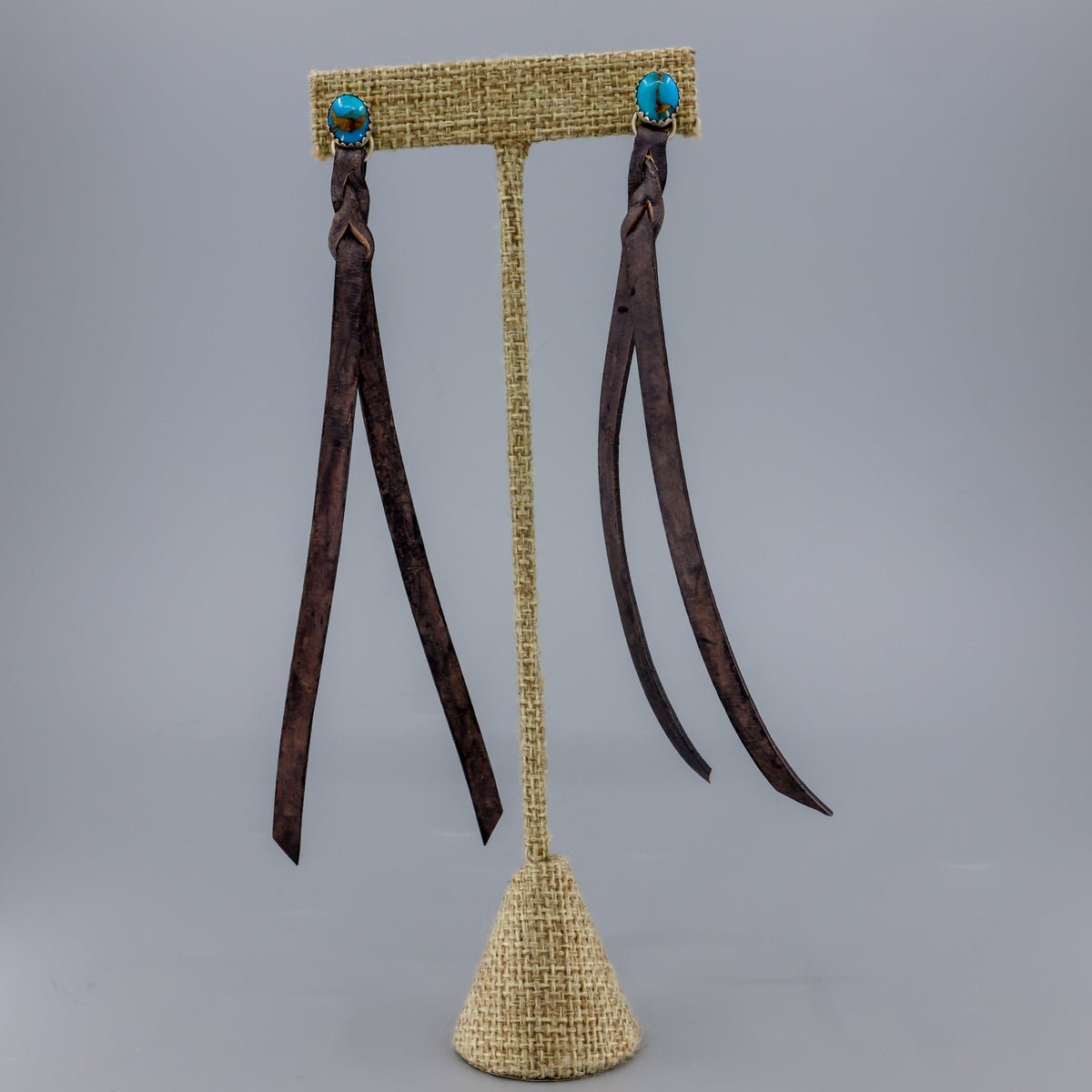 handmade turquoise earrings with distressed black leather fringe on a linen hanger