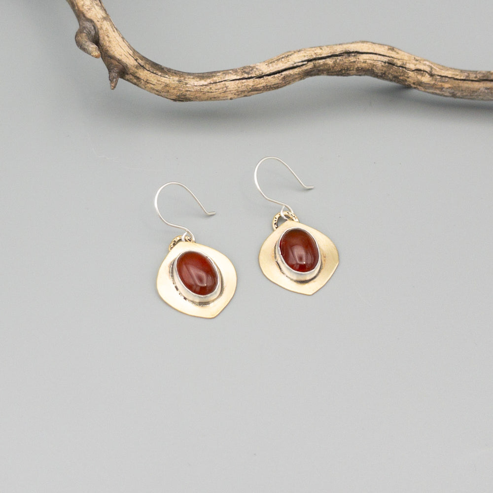Brass, sterling silver, and carnelian handmade earrings on a gray background