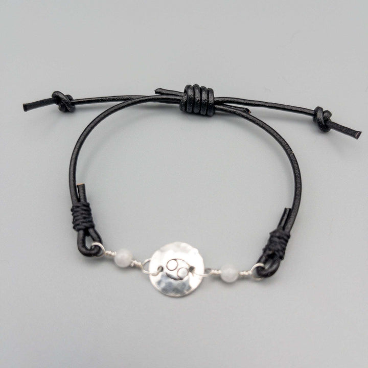 Cancer zodiac bracelet with moonstone beads and stamped sterling silver disc on gray background