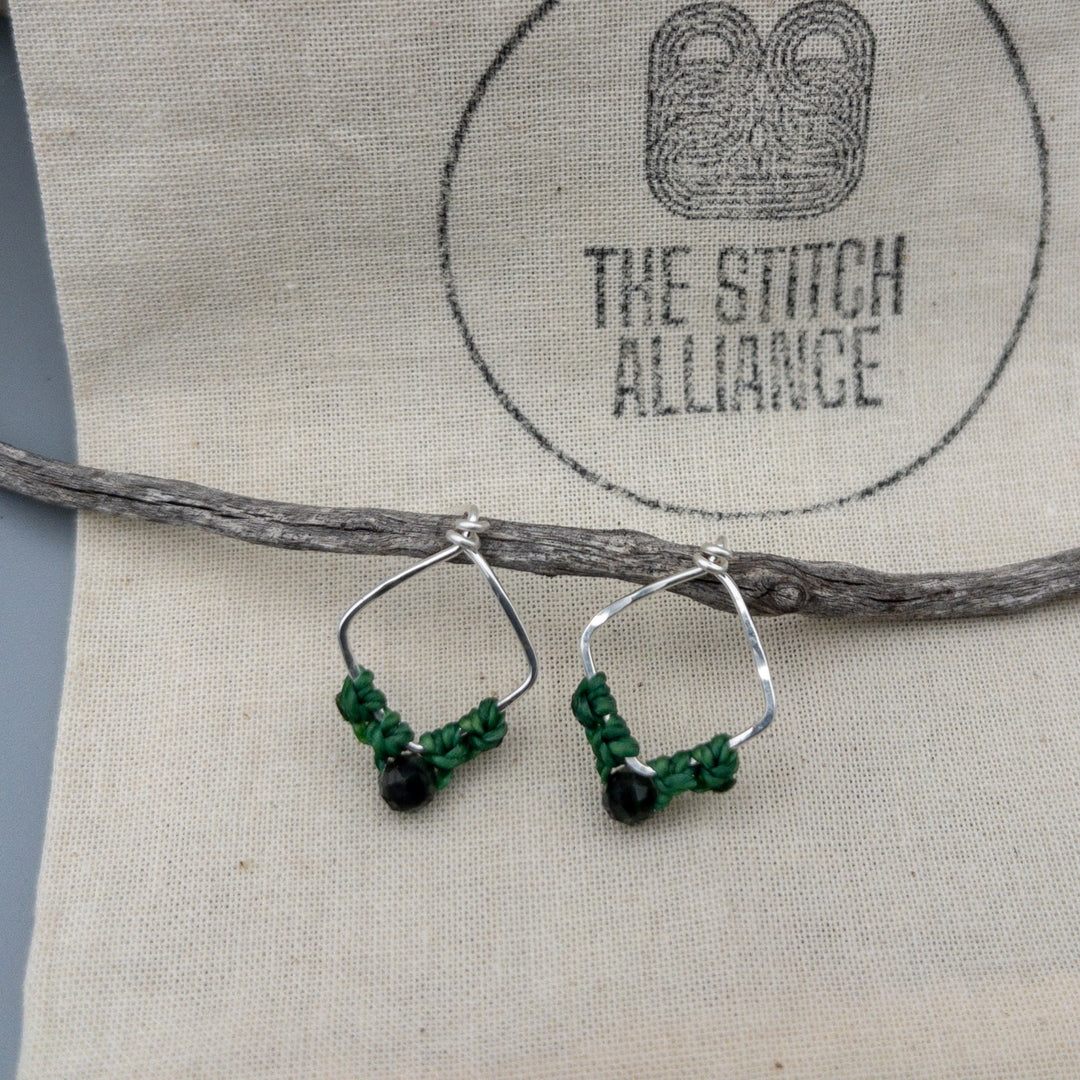 Cancer emerald sterling silver earrings on a muslin bag