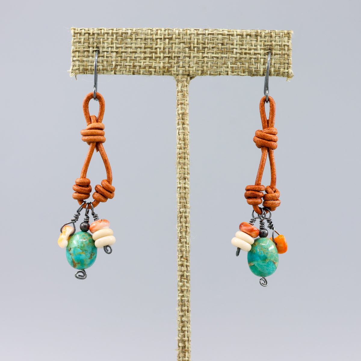 handmade turquoise, spiny oyster, leather, oxidized sterling silver charm earrings on a linen hanger