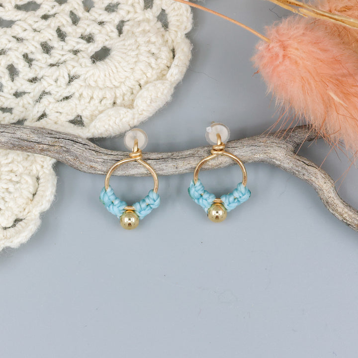 small, handmade gold macrame earrings in blue overhead view