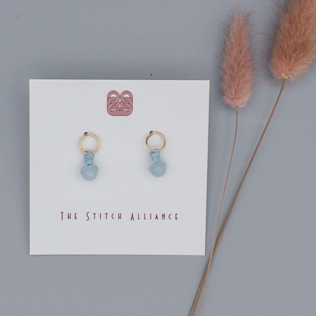 14k gold filled post style earrings with an aquamarine bead on. a gray background