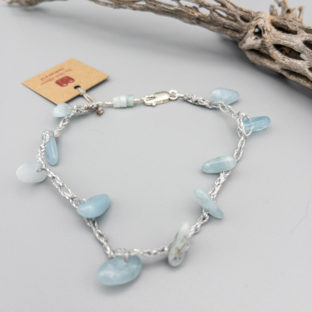 aquamarine crochet anklet with sterling silver clasp on a gray background
