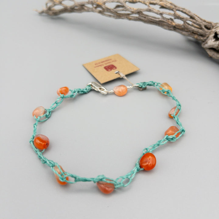 carnelian bead crochet anklet with sterling silver clasp on a gray background
