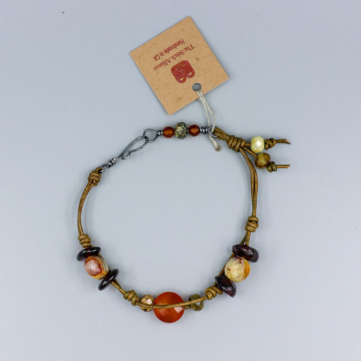 handmade leather and gemstone bracelt with garnet, carnelian, crazy lace agate, and hessonite with oxidized sterling silver clasp overhead view