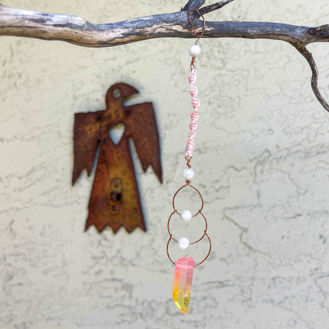 copper, moonstone, and crystal suncatcher made with macrame the colors are reminiscent of a sunset