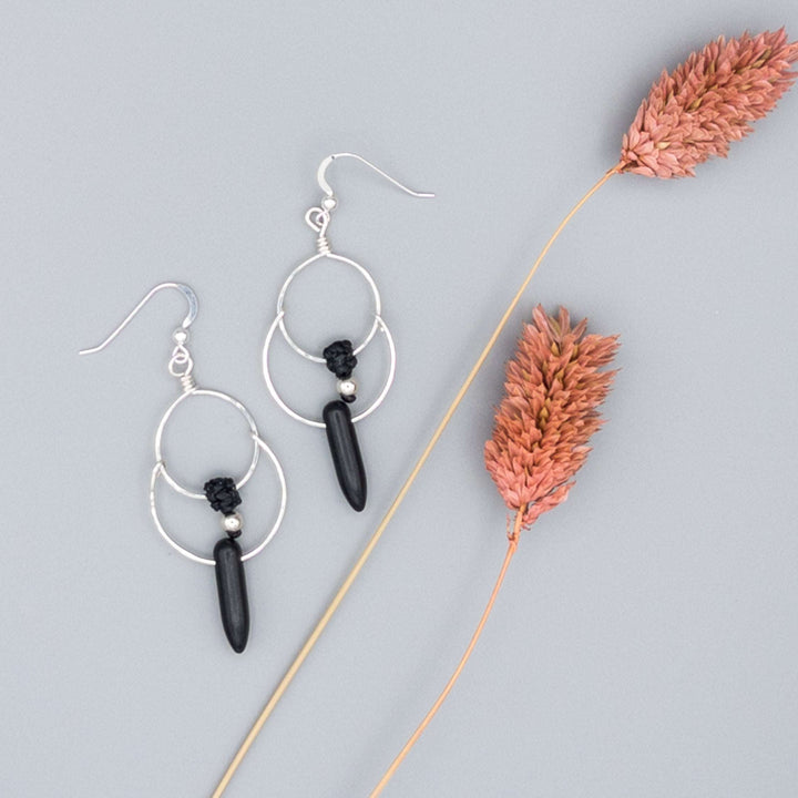 Close up of Sterling silver double hoop earrings. Handcrafted and hand-hammered with black howlite spike shaped beads.