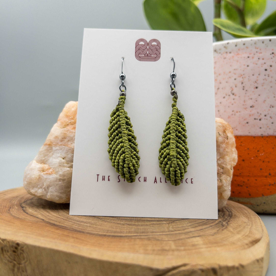 Olive green macrame feather earrings with oxidized sterling silver ear wires on white background