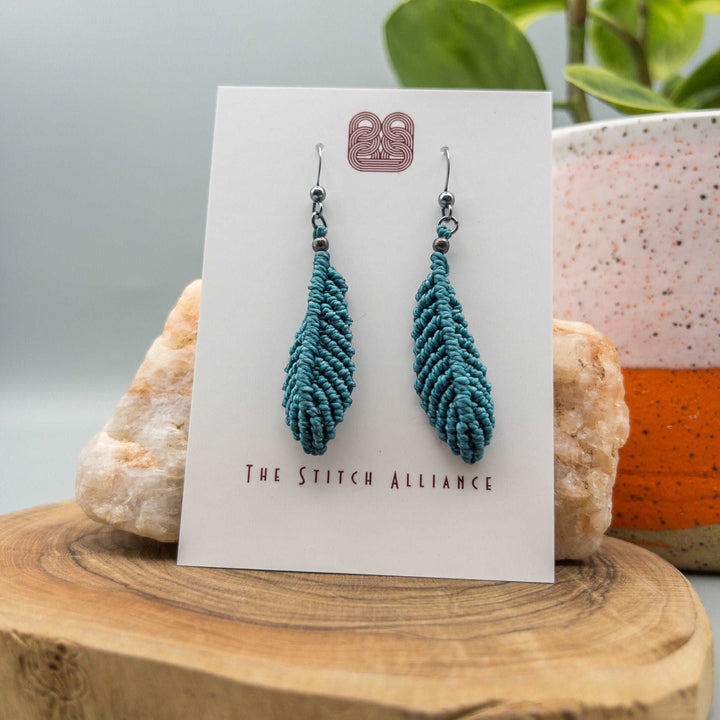 Rich teal macrame feather earrings with oxidized sterling silver ear wires on white background