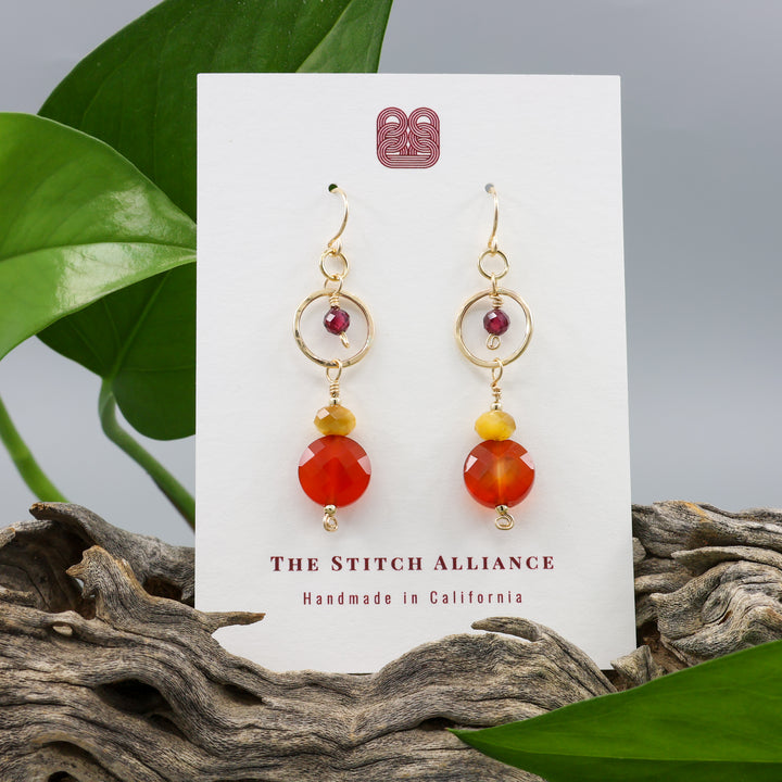 Carnelian, tiger's eye, and garnet gold filled dangle earrings on a white display card