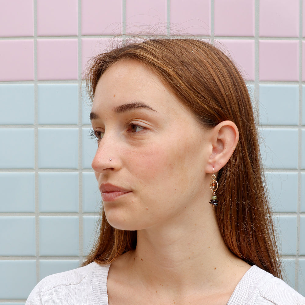 handmade gold dangle earrings with garnet and hessonite beads worn on a model