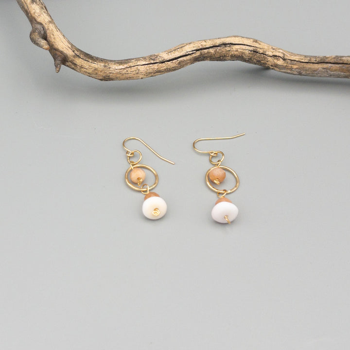 Gold fill, peach moonstone, and queen conch shell handmade earrings on a gray background