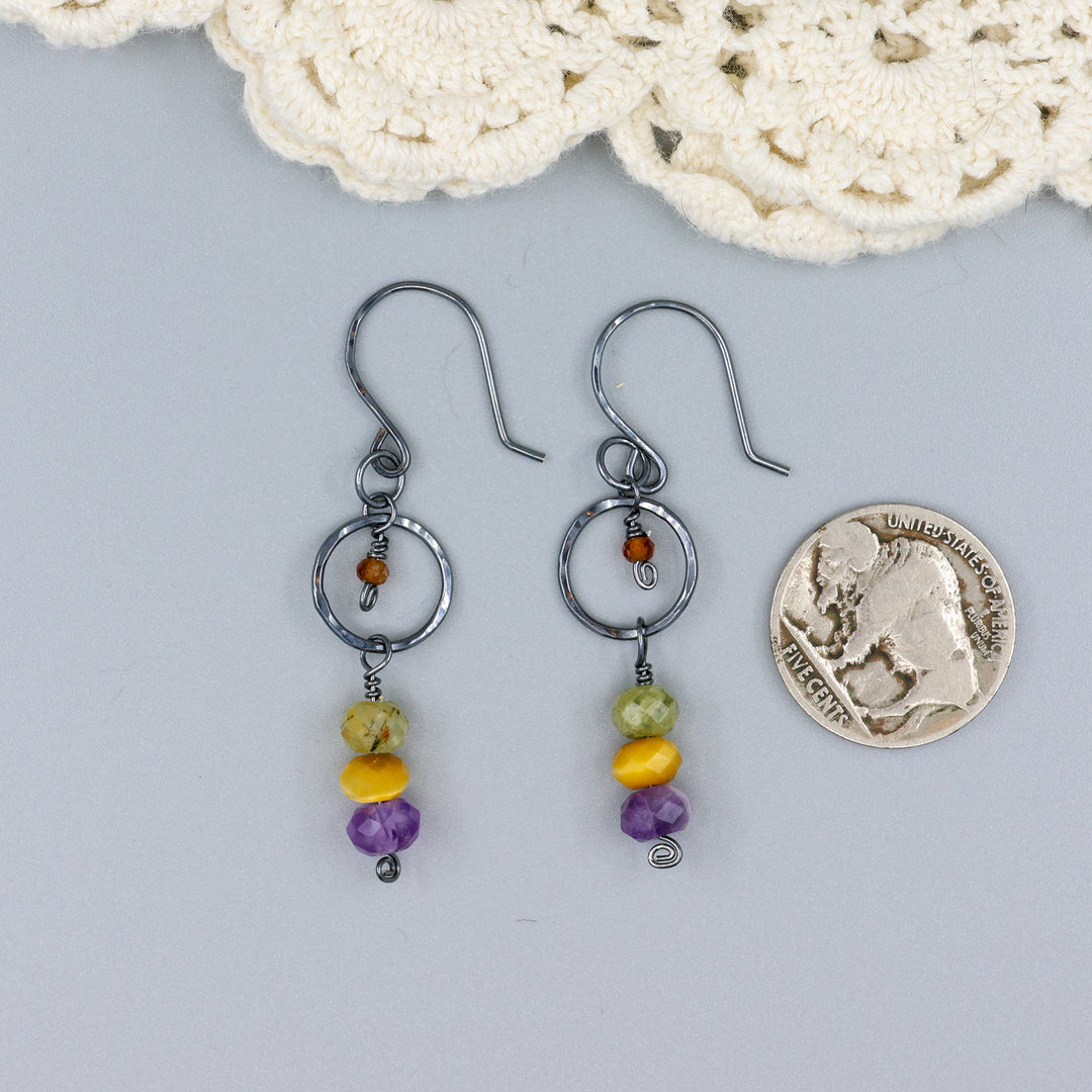 handmade oxidized sterling silver, amethyst, golden tigers eye, green garnet, and hessonite dangle earrings with a nickel for size comparison