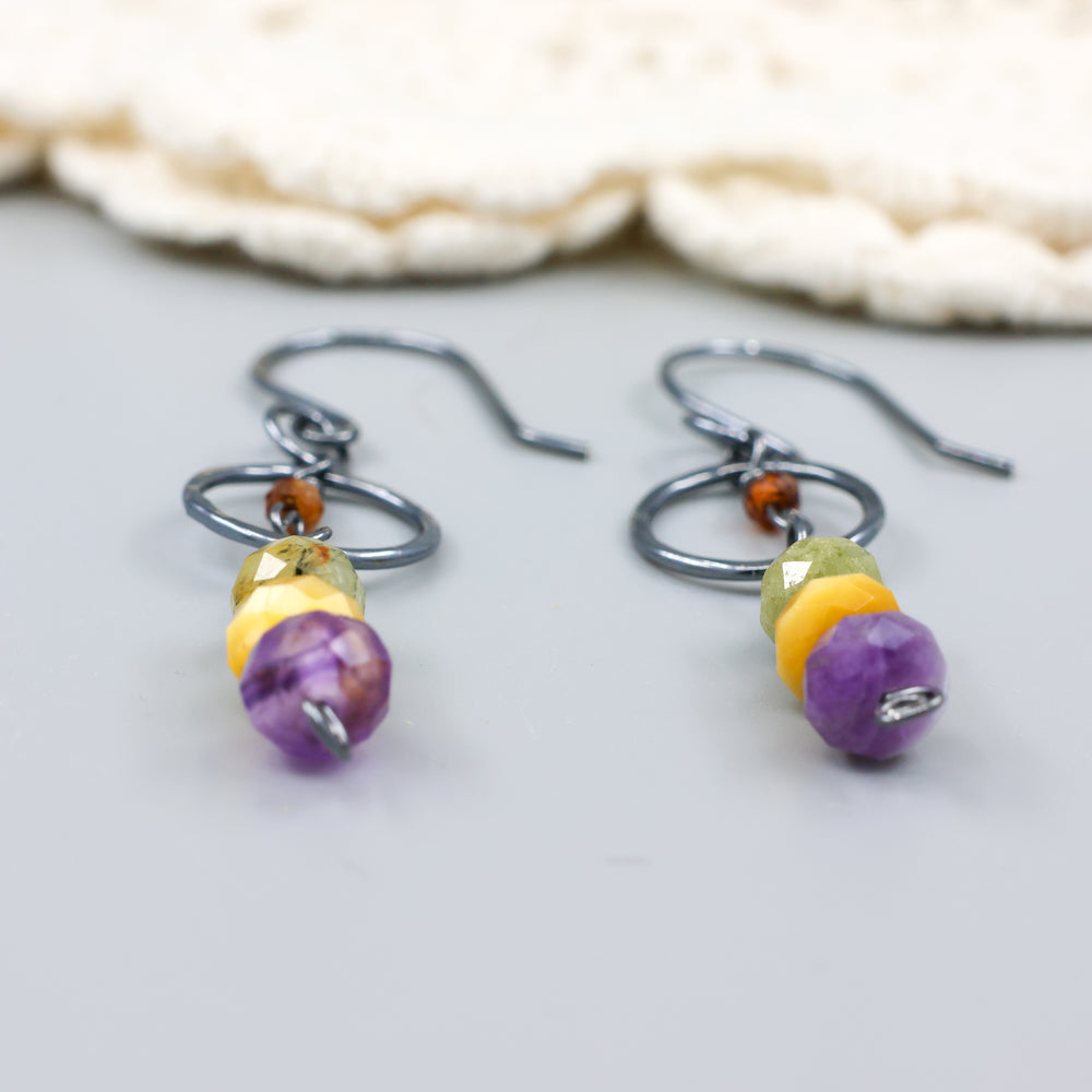 close up view of handmade oxidized sterling silver, amethyst, golden tigers eye, green garnet, and hessonite dangle earrings