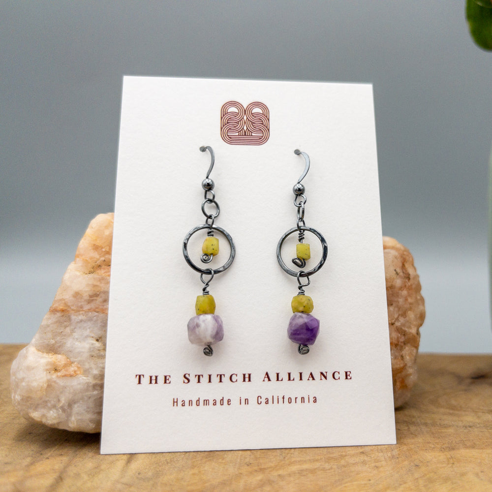 Oxidized sterling silver, amethyst, and afghan jade earrings on a white card