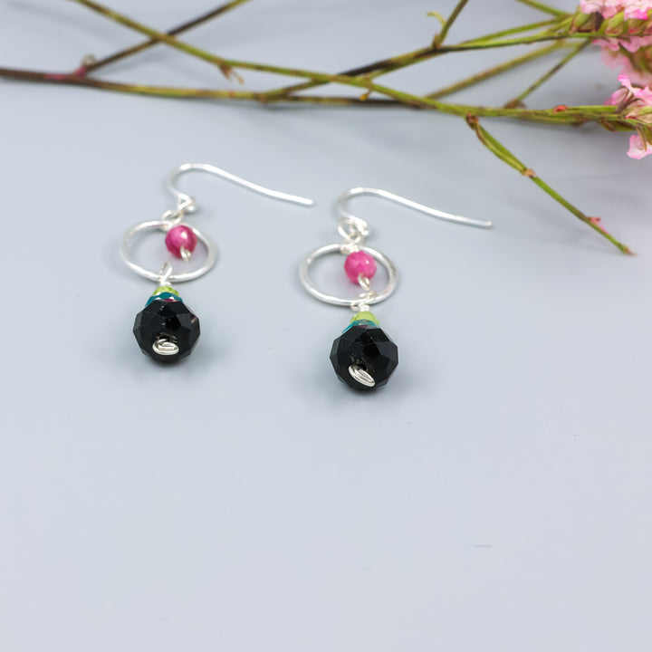 detail view of handmade gemstone and sterling silver dangle earrings with black tourmaline, blue apatite, peridot, and pink tourmaline