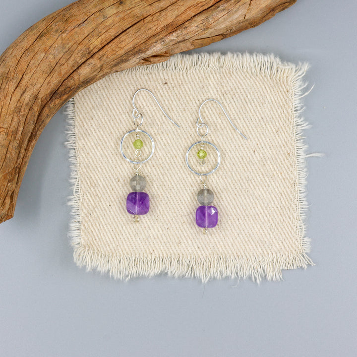handmade amethyst, labradorite, and peridot sterlign silver earrings on an off whte background