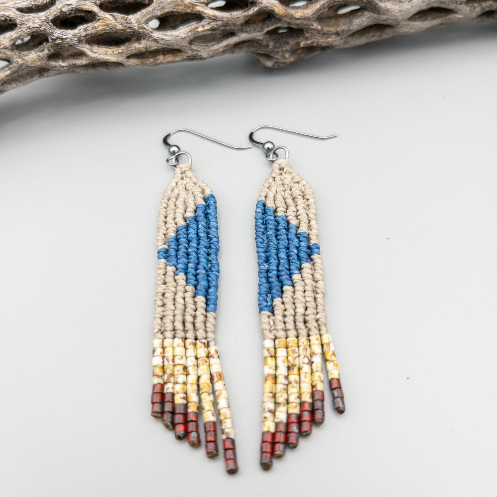close up view of blue, tan, and red handwoven macrame earrings with seed bead fringe