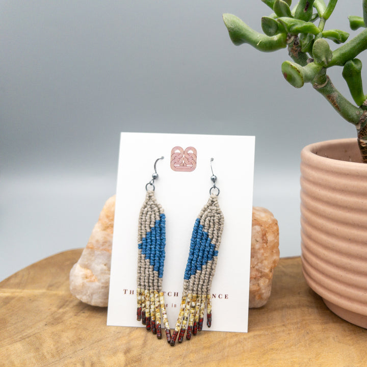 blue, tan, and red handwoven macrame earrings with seed bead fringe on a white card