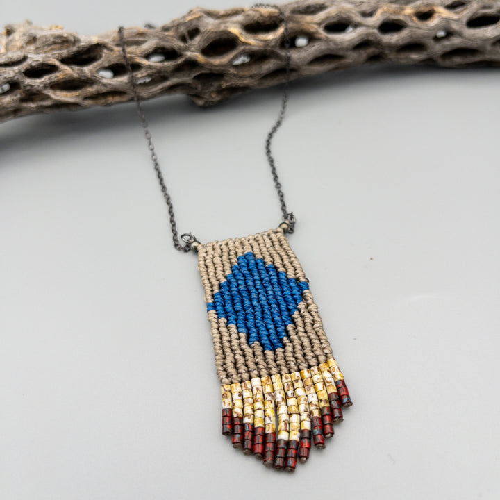 close up of Handwoven four elements macrame necklace in blue and tan with tan and red seed bead fringe