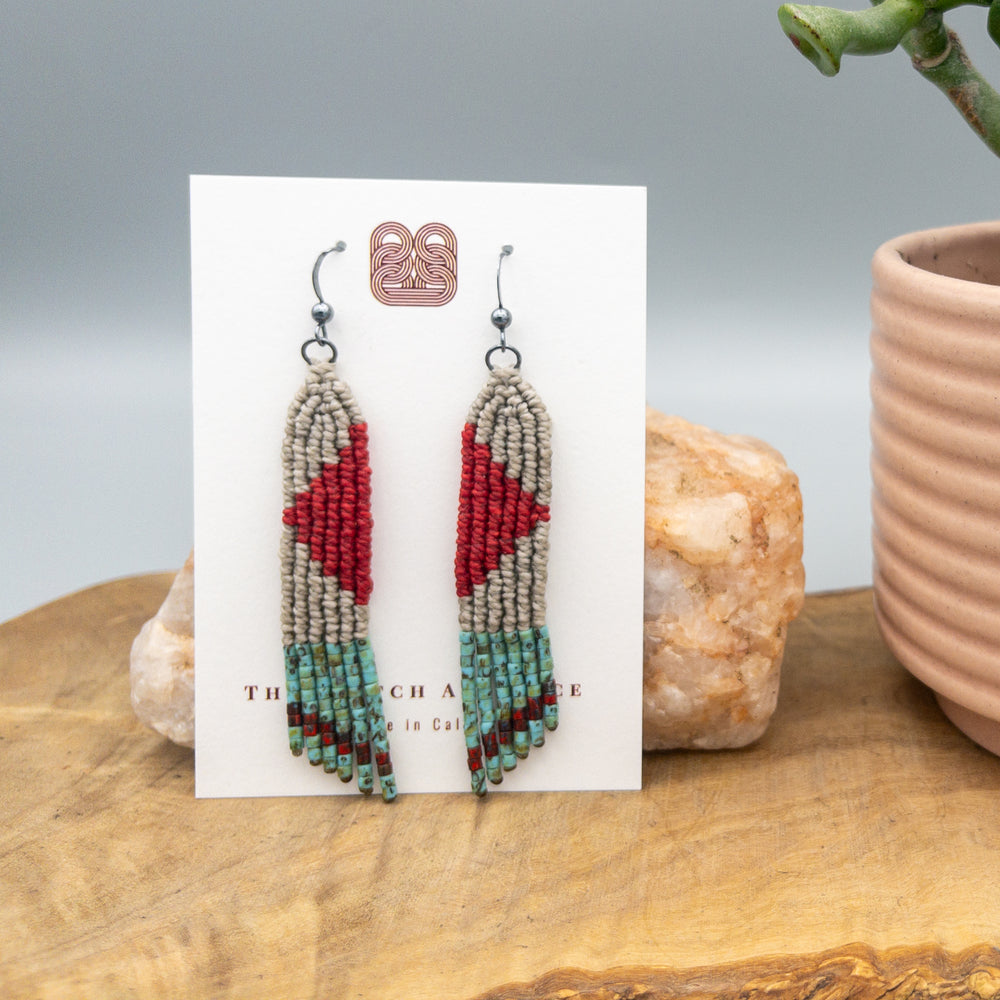 red, tan, and turquoise four elements macrame earrings with seed bead fringe on a white card