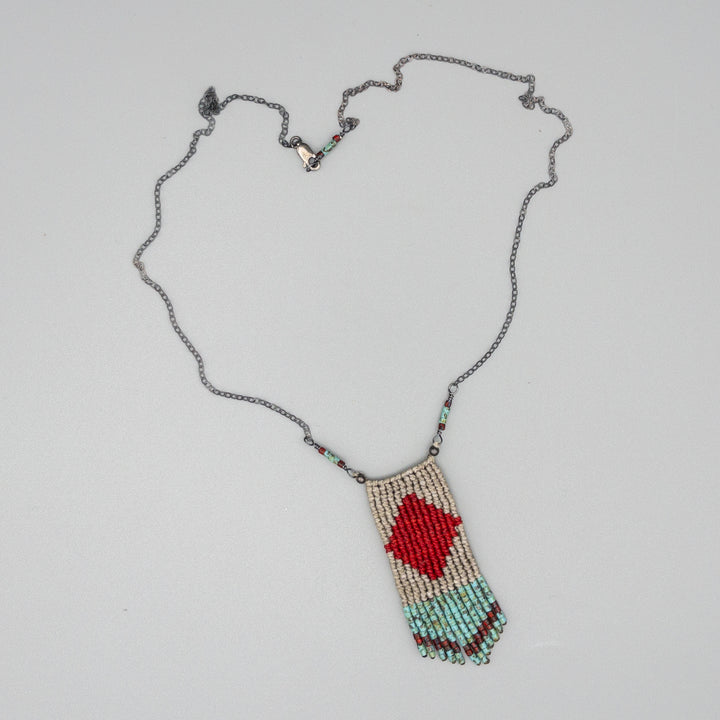 red, tan, and turquoise four elements macrame necklace with seed bead fringe on a gray background