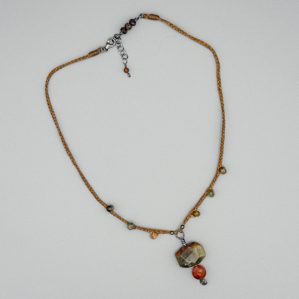 green garnet and carnelian amulet necklace on a gray background