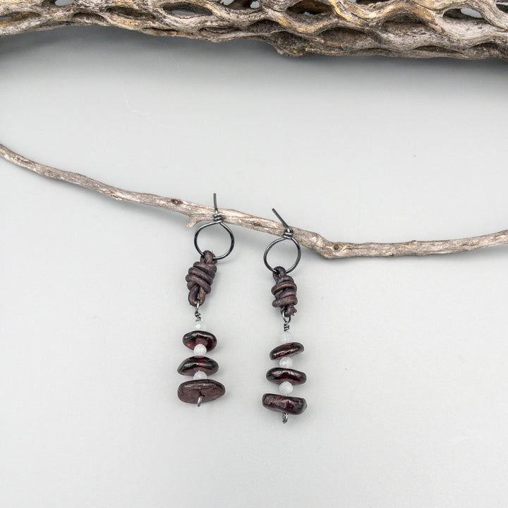 Garnet and aquamarine sterling silver leather drop earrings on a gray background