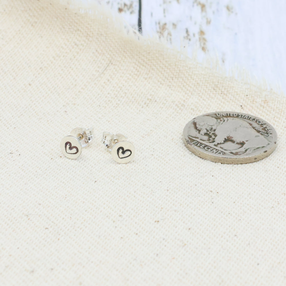 handmade minimalist heart stamp sterling silver stud earrings with a coin for size comparison