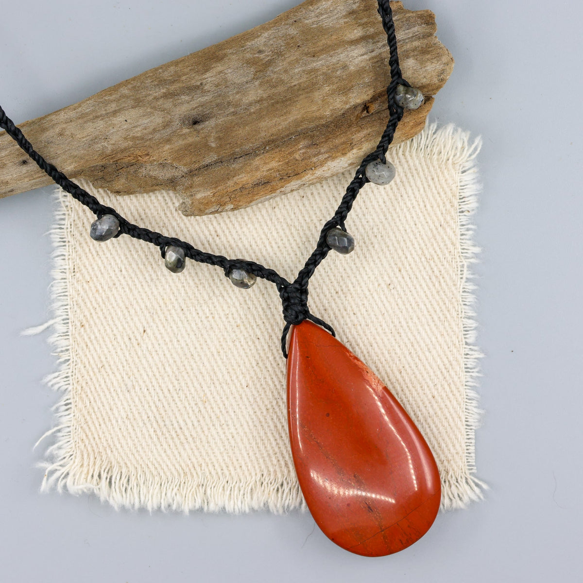 red jasper & larvikite bradied necklace with sterling silver clasp on an off white background