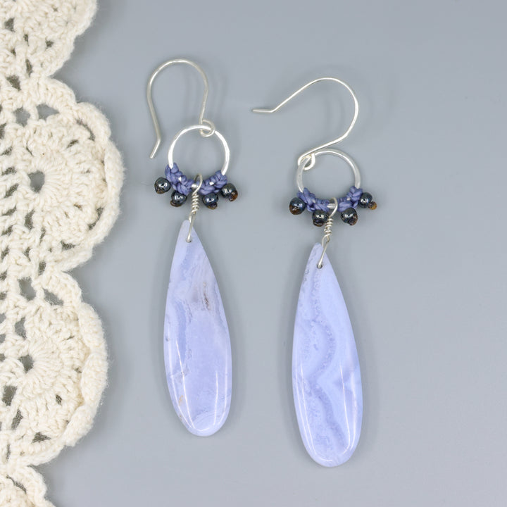 handmade, sterling silver and blue lace agate dangle earrings on a gray background