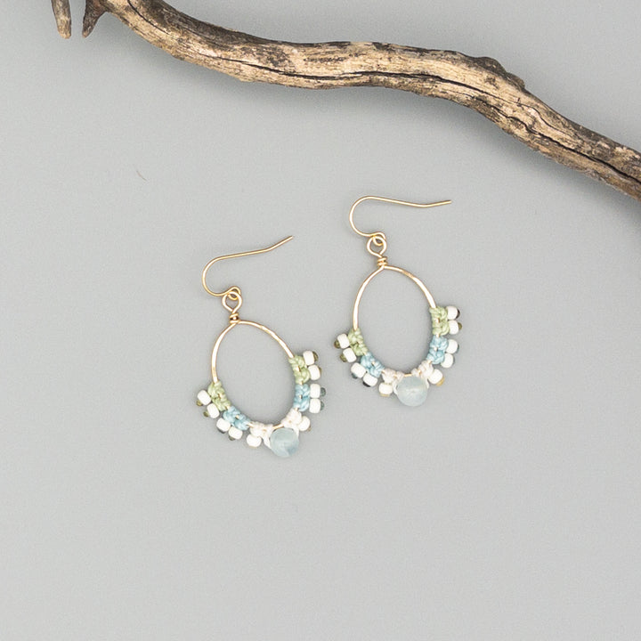 gold fill macrame hoop earrings with aquamarine beads shown on a gray background