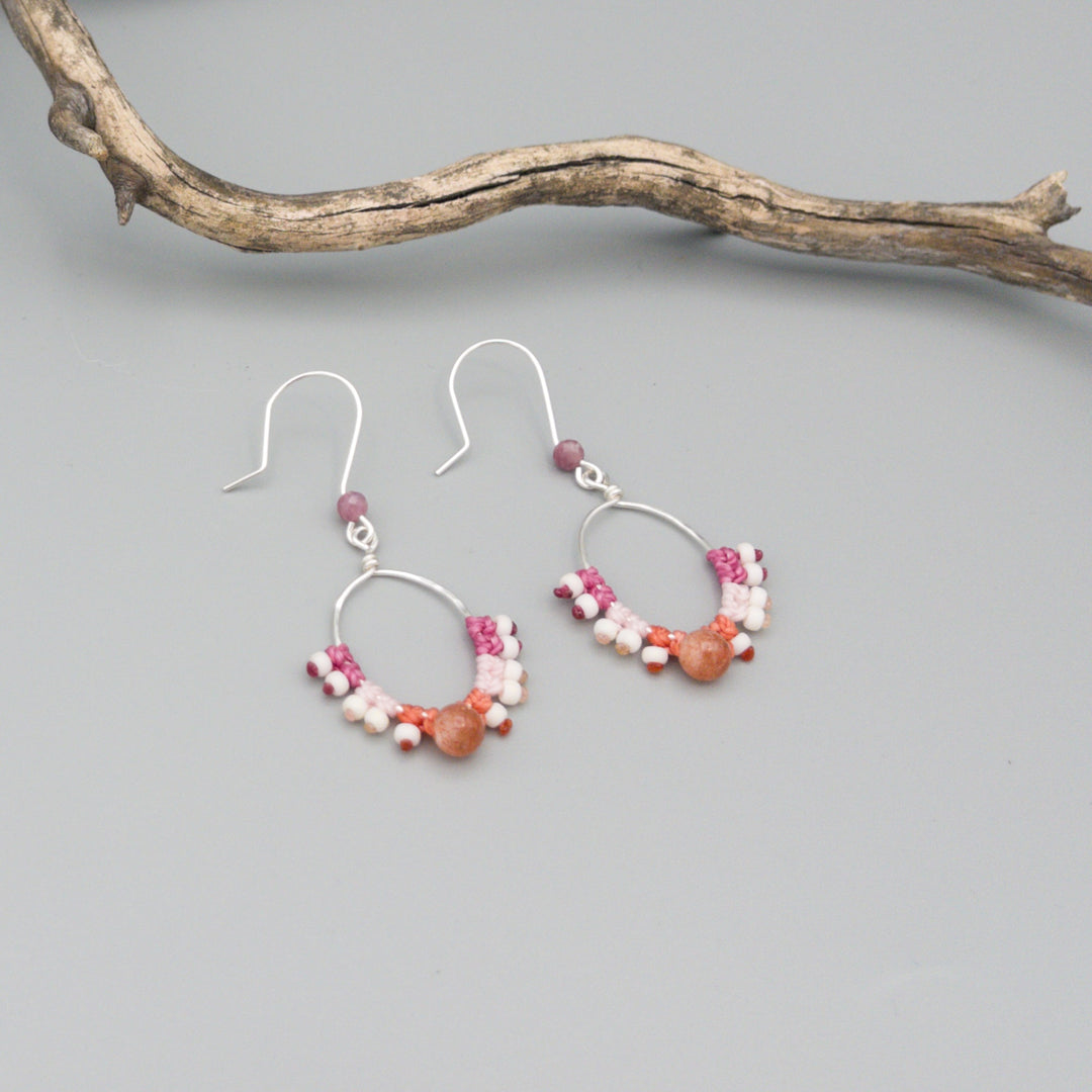 sterling silver pink macrame hoop earrings with sunstone bead on a gray background