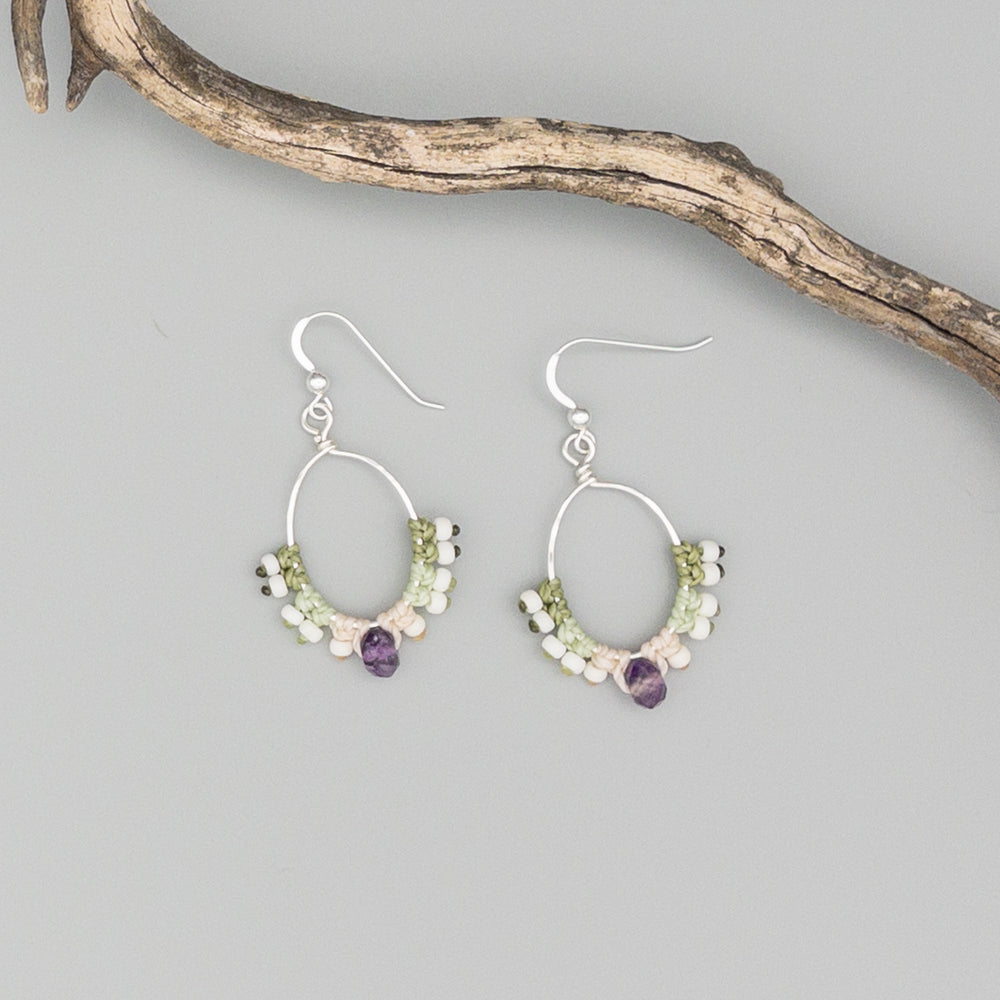sterling silver, amethyst, and seed bead macrame hoop earrings shown on a gray background