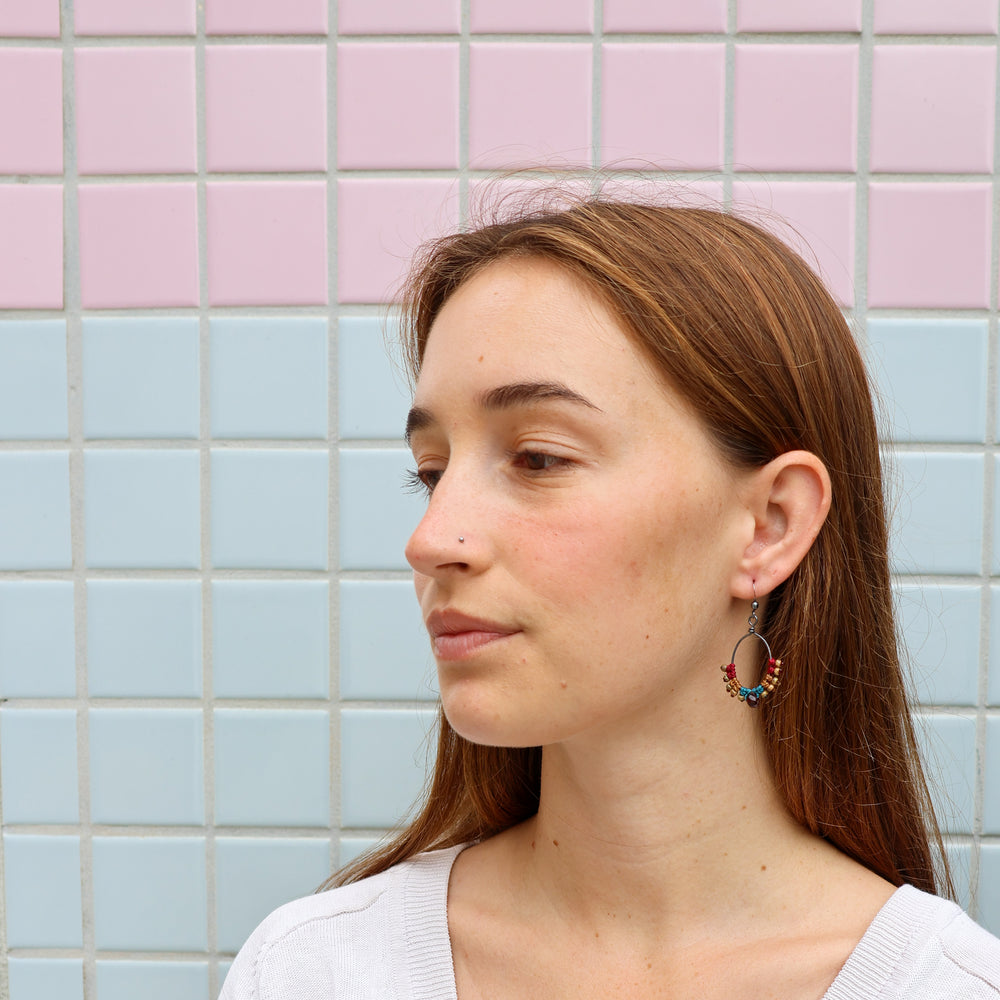 handmade macrame hoop earrings with garnet bead worn on a model