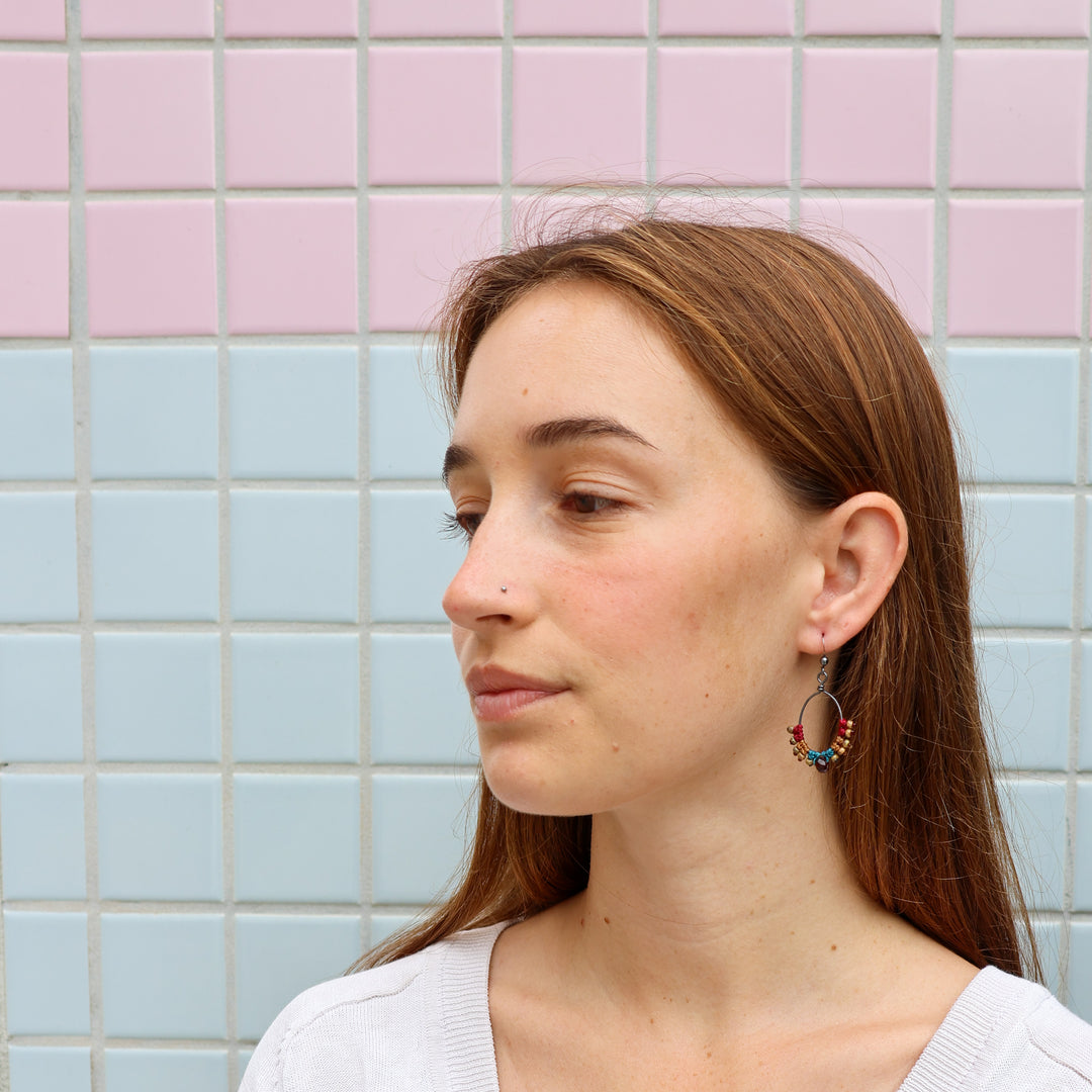 handmade macrame hoop earrings with garnet bead worn on a model