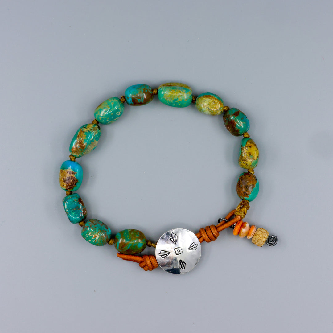 Kingman turquoise bead leather and sterling silver bracelet handmade in california on a gray background