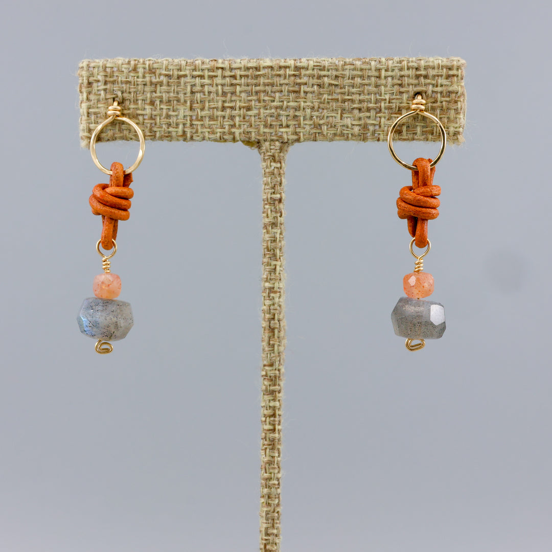 labradorite and sunstone gold earrings with leather details on a linen hanger