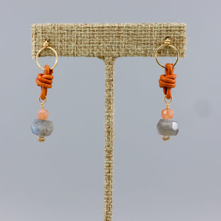 labradorite and sunstone gold earrings with leather details on a linen hanger