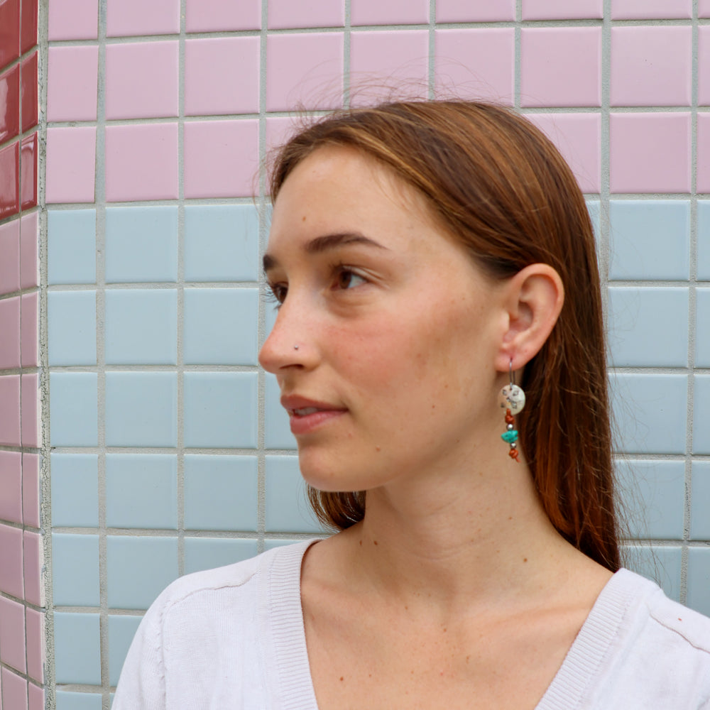 hand stamped sterling silver, leather, and turquoise earrings worn on a model