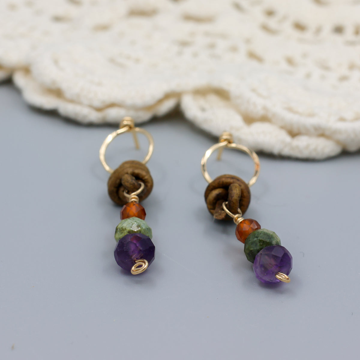 detail view of handmade amethyst, green garnet, and hessonite leather and gold fill earrings