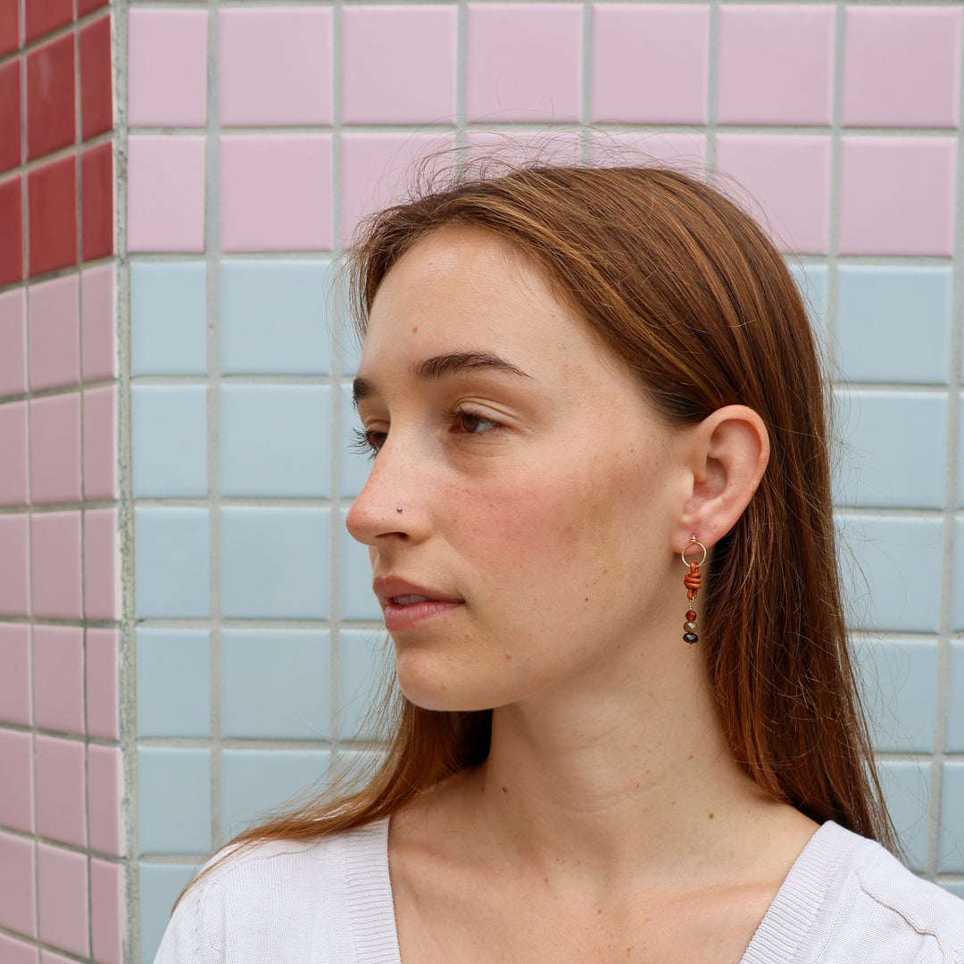 garnet, hessonite, and leather gold filled earrings worn on a model