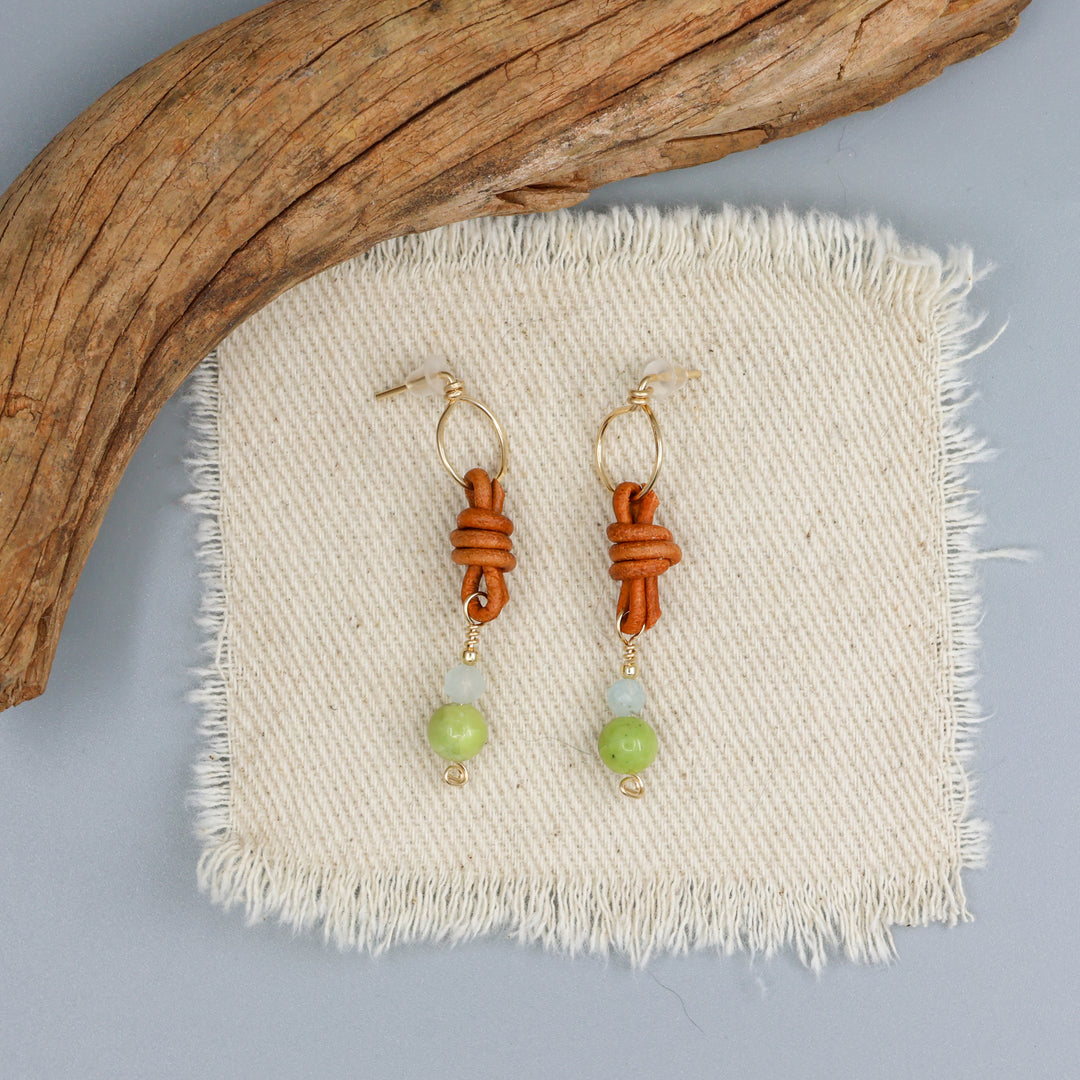 handmade peridot, aquamarine, and leather gold filled earrings on an off white background