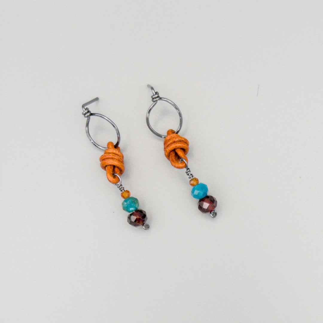 garnet, blue apatite, hessonite bead earrings with leather and oxidized sterling silver on a gray background