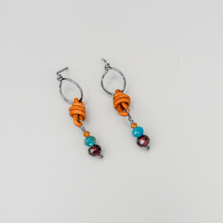 garnet, blue apatite, hessonite bead earrings with leather and oxidized sterling silver on a gray background