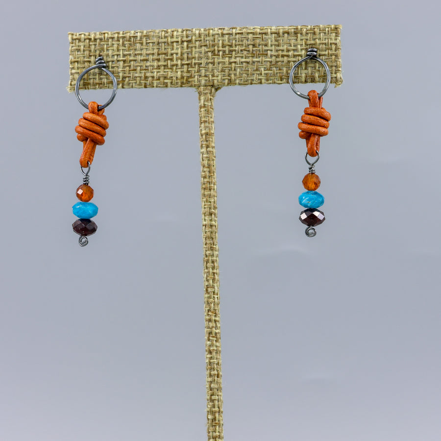 oxidized sterling, leather, garnet, apatite and hessonite handmade earrings on a gray background