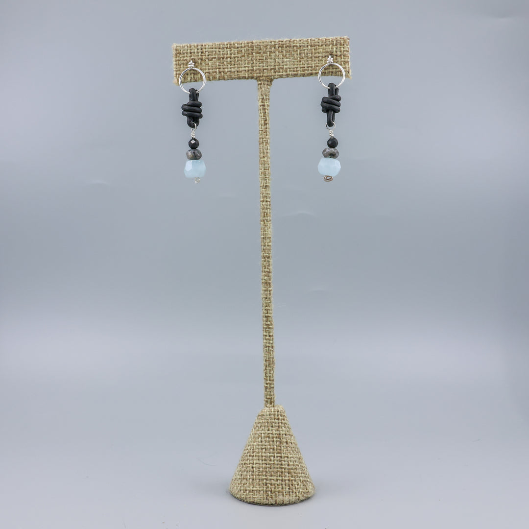 handmade aquamarine, larvakite, and black spinel leather & sterling silver earrings on a linen display hanger